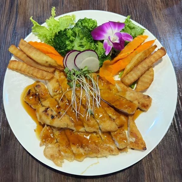 Asuka Japanese Cuisine's chicken teriyaki with fries, broccoli, carrots, radishes, and a purple orchid.